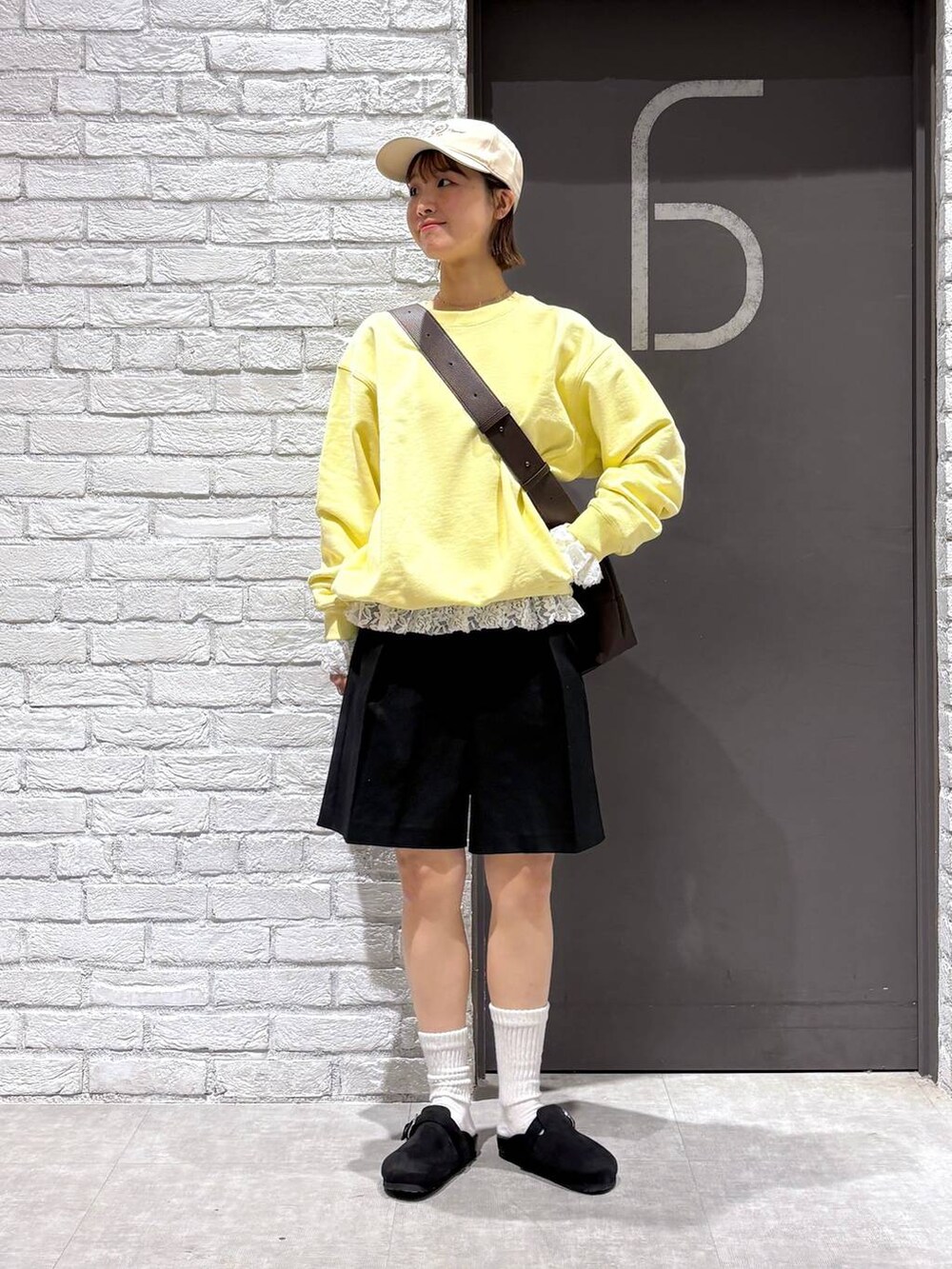 ブラウン系のショルダーバッグ、イエロー系のスウェット、ブラック系のスラックスを着用したレディースの冬コーディネートの2枚目の写真