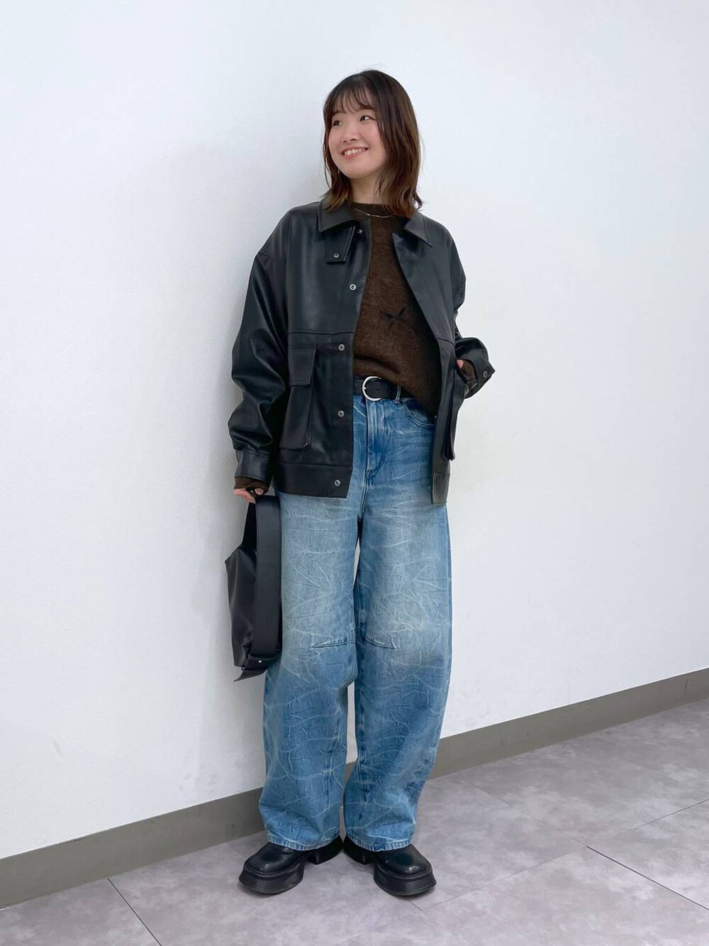 ブラック系のブーツ、ブラック系のショルダーバッグ、ブルー系のデニムパンツを着用したレディースの冬コーディネートの6枚目の写真