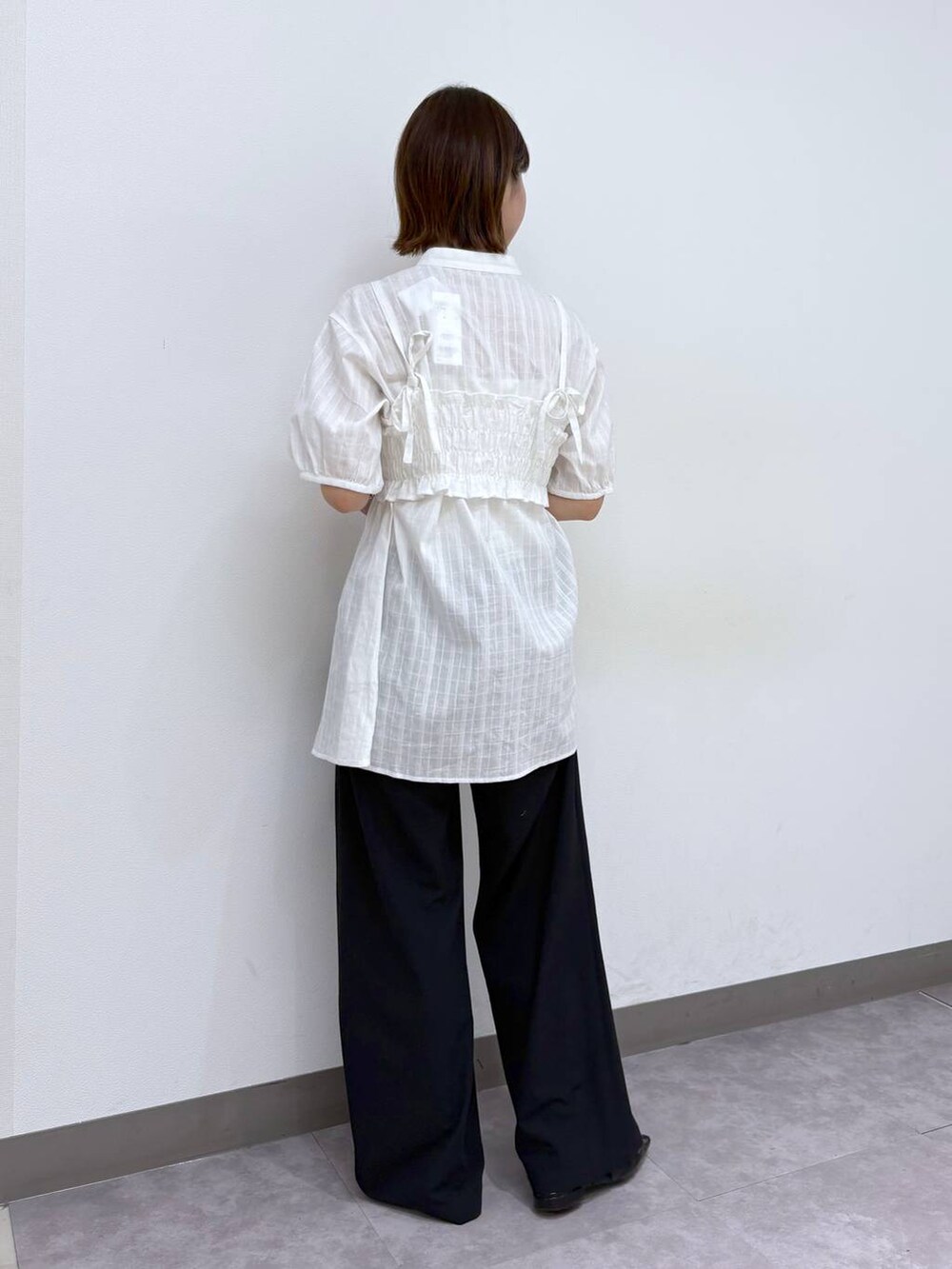 ブラック系のスラックス、ホワイト系のシャツ/ブラウス、ブラック系のハンドバッグを着用したレディースの春コーディネートの4枚目の写真