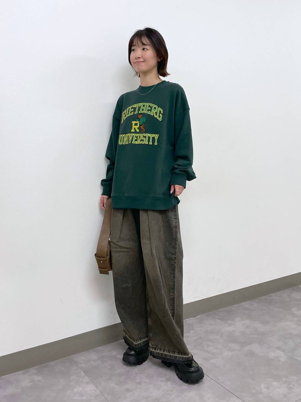 ブラウン系のショルダーバッグ、ブラック系のローファー、グリーン系のスウェットを着用したレディースの冬コーディネートの5枚目の写真