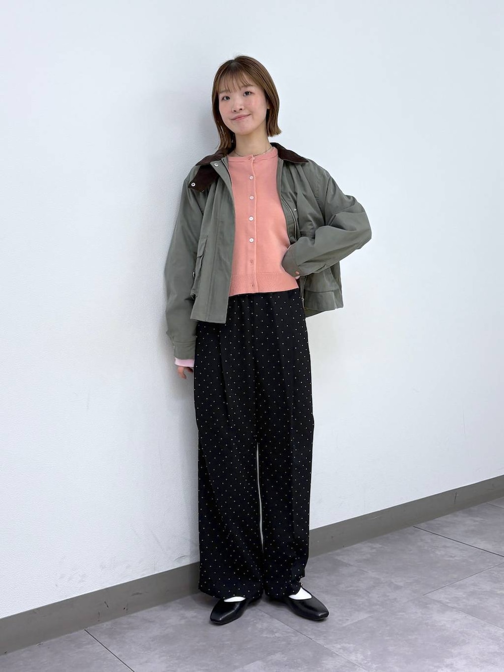 ブラック系のパンプス、ブラック系のスラックス、グリーン系のブルゾンを着用したレディースの春コーディネートの4枚目の写真