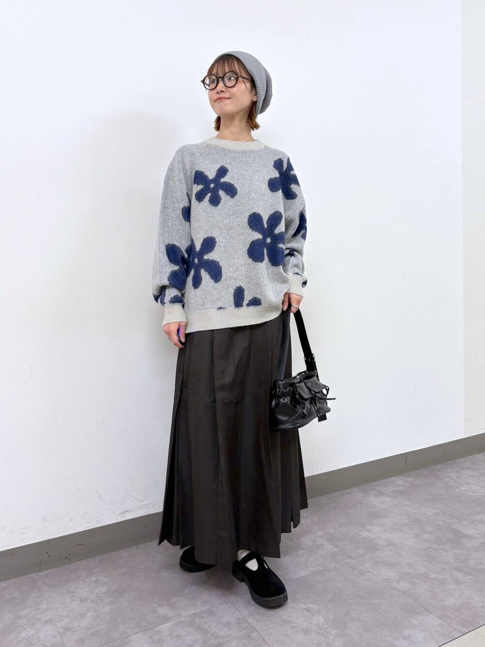 ホワイト系のニット/セーター、ブラウン系のスカート、ブラック系のショルダーバッグを着用したレディースの秋コーディネートの2枚目の写真