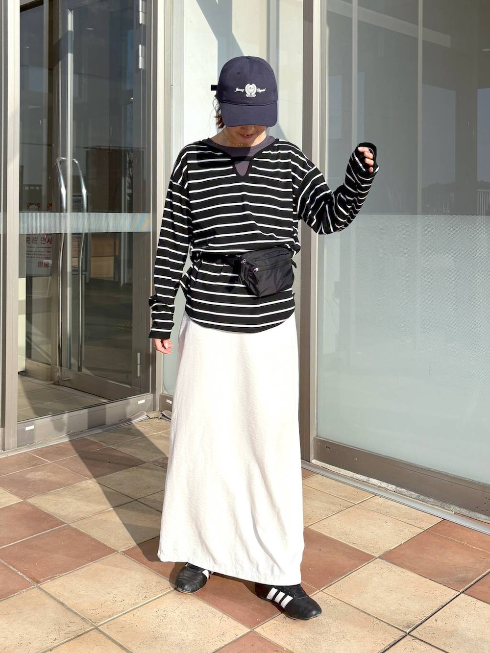 ブラック系のボディバッグ/ウエストポーチ、グレー系のTシャツ/カットソー、ホワイト系のスカートを着用したレディースの春コーディネートの4枚目の写真