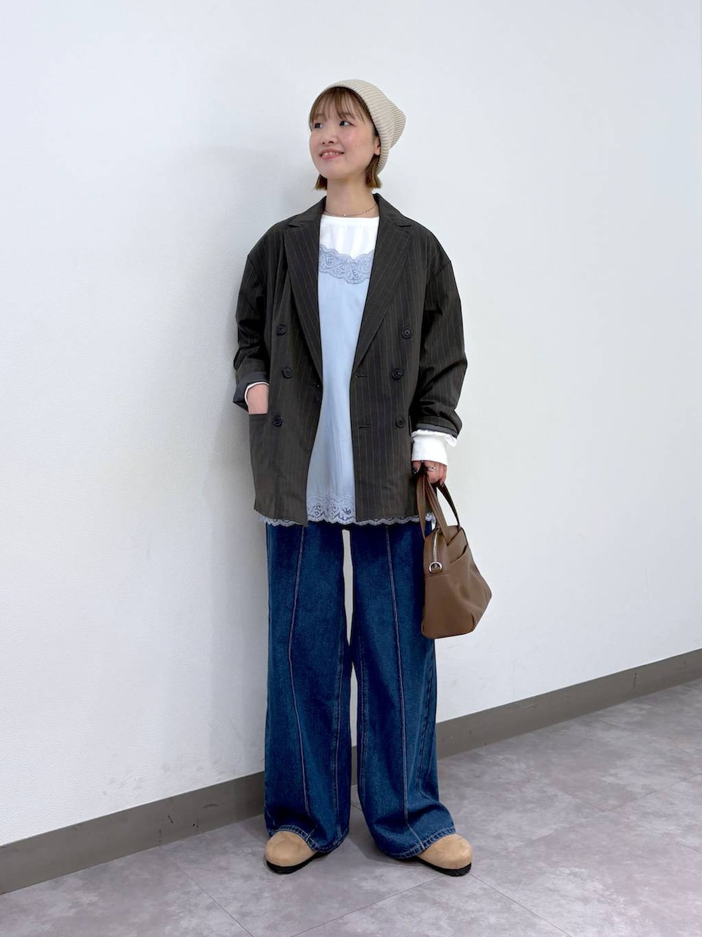 グレー系のテーラードジャケット、ブラウン系のボストンバッグ、ブルー系のデニムパンツを着用したレディースの冬コーディネートの6枚目の写真