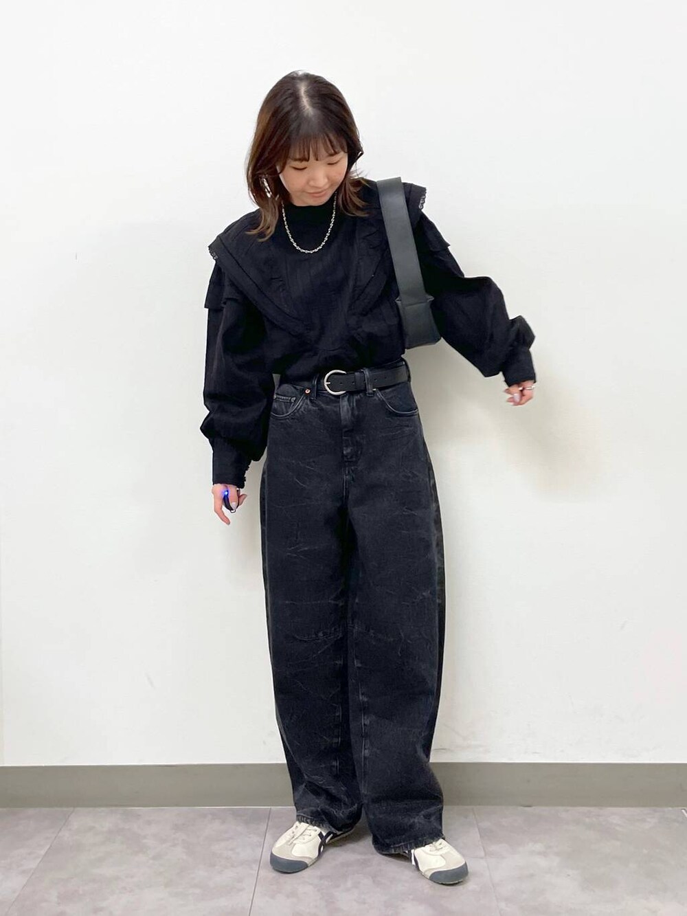 ブラック系のシャツ/ブラウス、ブラック系のショルダーバッグ、ブラック系のデニムパンツを着用したレディースの秋コーディネートの3枚目の写真