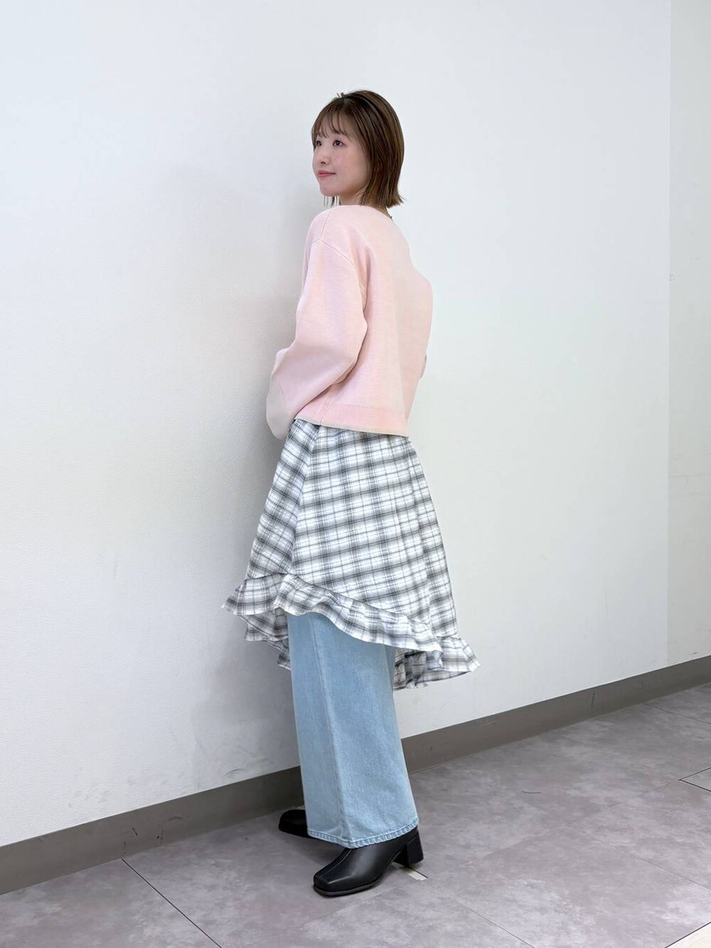 ブルー系のデニムパンツ、ピンク系のカーディガン/ボレロ、ブラック系のブーツを着用したレディースの冬コーディネートの3枚目の写真