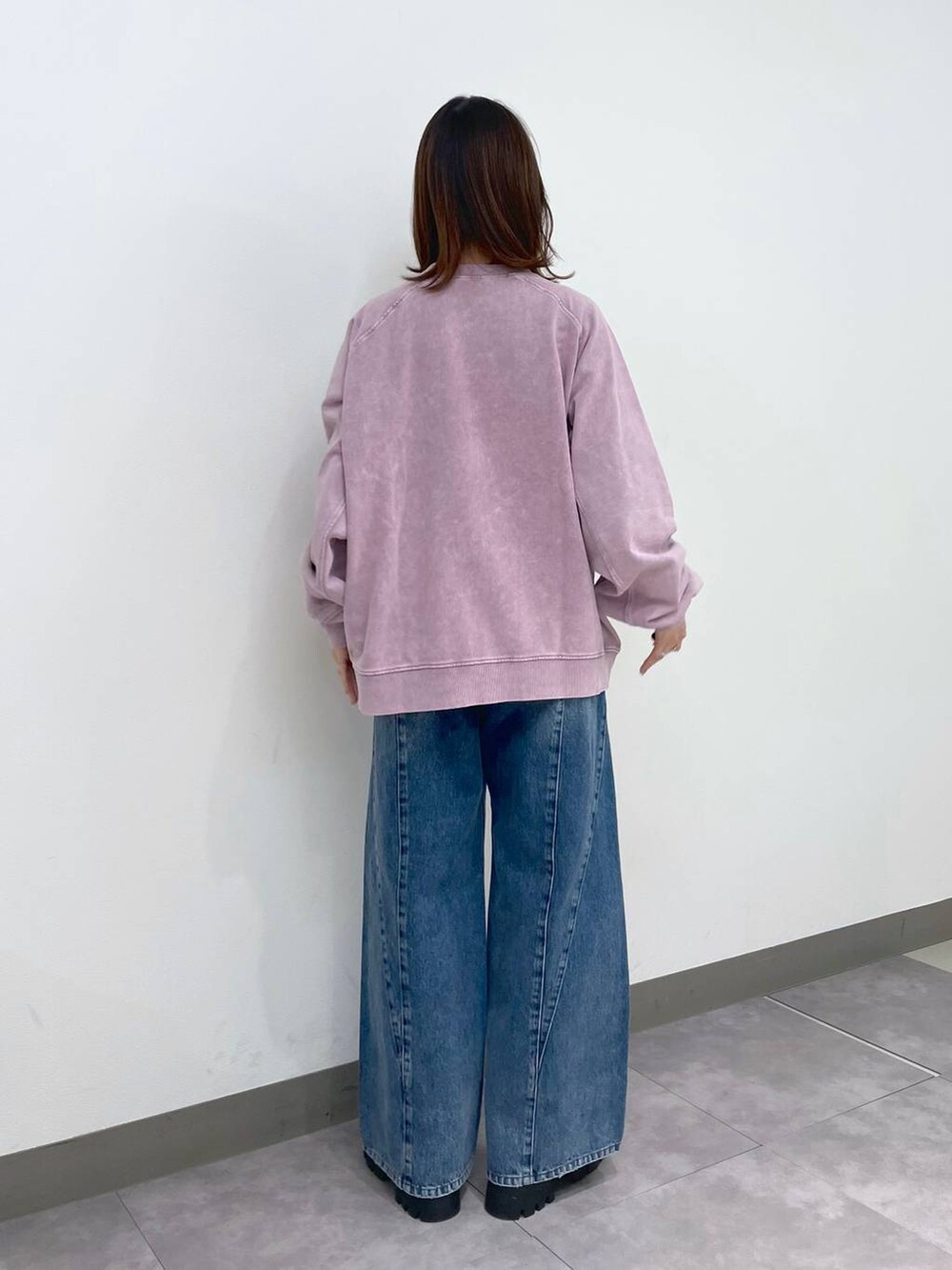 ブラック系のブーツ、ピンク系のスウェット、ブルー系のデニムパンツを着用したレディースの冬コーディネートの5枚目の写真