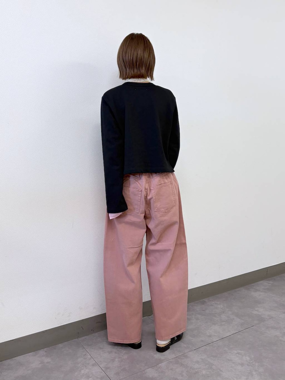 ブラック系のパンプス、ブラック系のカーディガン/ボレロ、ピンク系のデニムパンツを着用したレディースの冬コーディネートの4枚目の写真