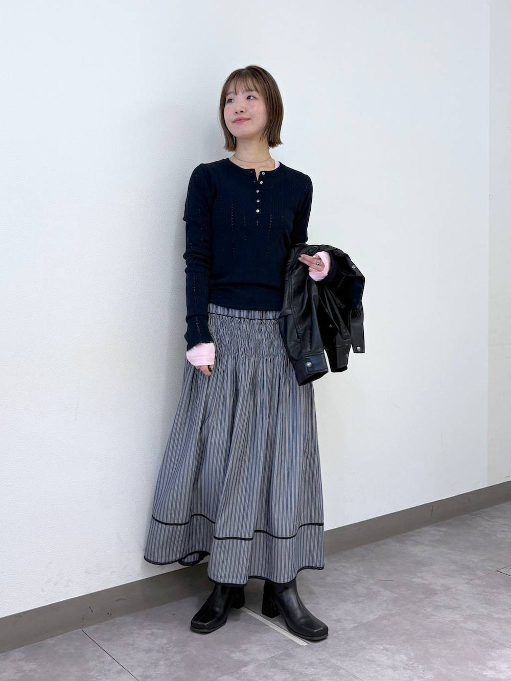 グレー系のスカート、ブラック系のブルゾン、ブルー系のニット/セーターを着用したレディースの冬コーディネートの4枚目の写真