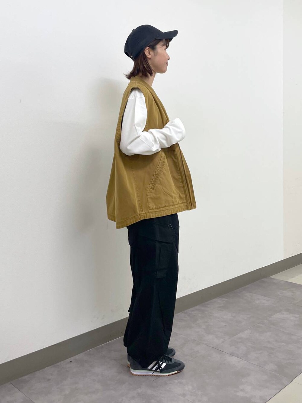 ブラック系のカーゴパンツ、ブラウン系のベスト、ホワイト系のTシャツ/カットソーを着用したレディースの秋コーディネートの3枚目の写真
