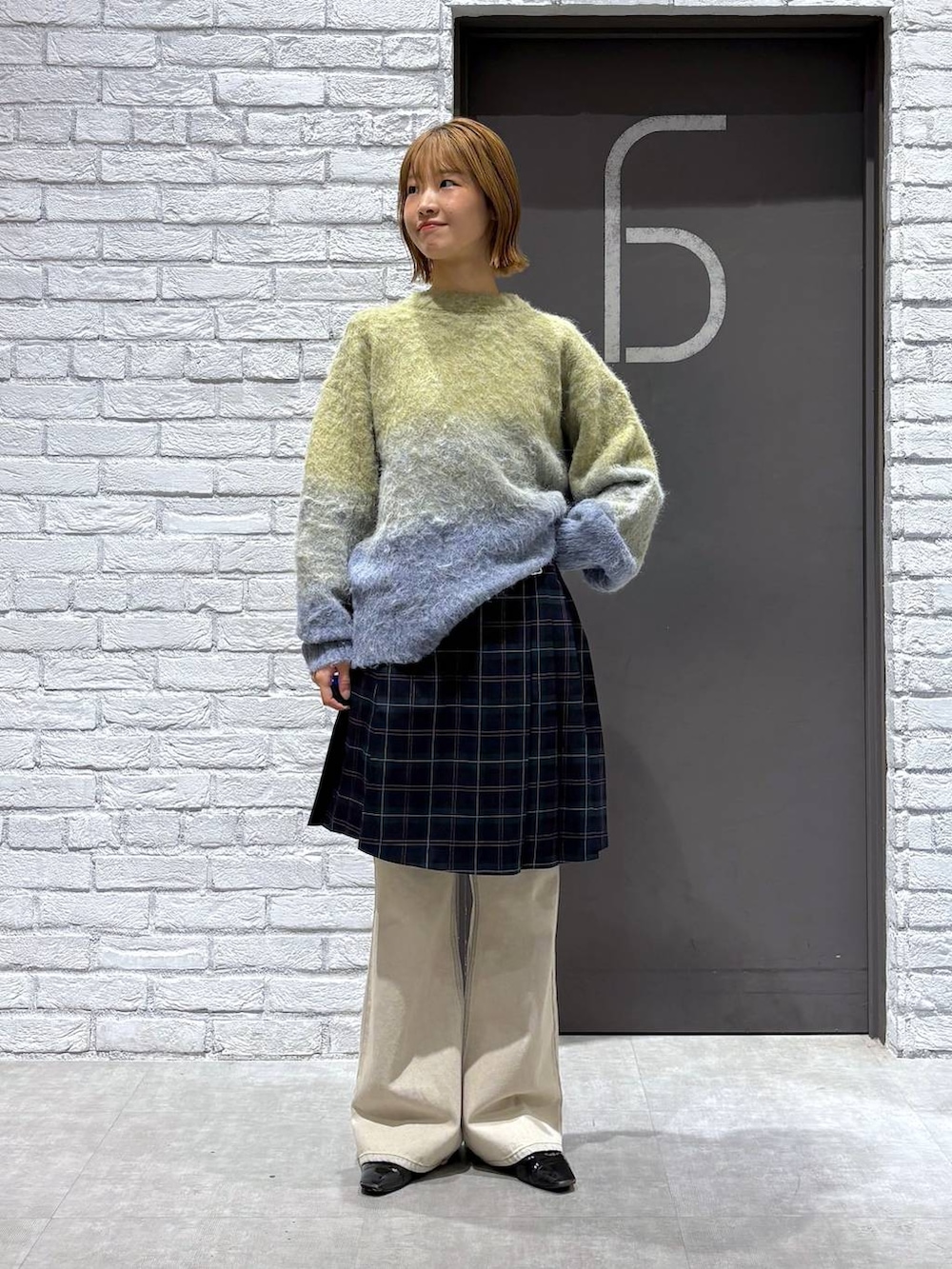 ホワイト系のデニムパンツ、グリーン系のスカート、イエロー系のニット/セーターを着用したレディースの秋コーディネートの5枚目の写真