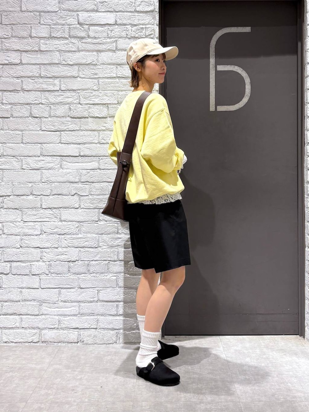 ブラウン系のショルダーバッグ、イエロー系のスウェット、ブラック系のスラックスを着用したレディースの冬コーディネートの5枚目の写真