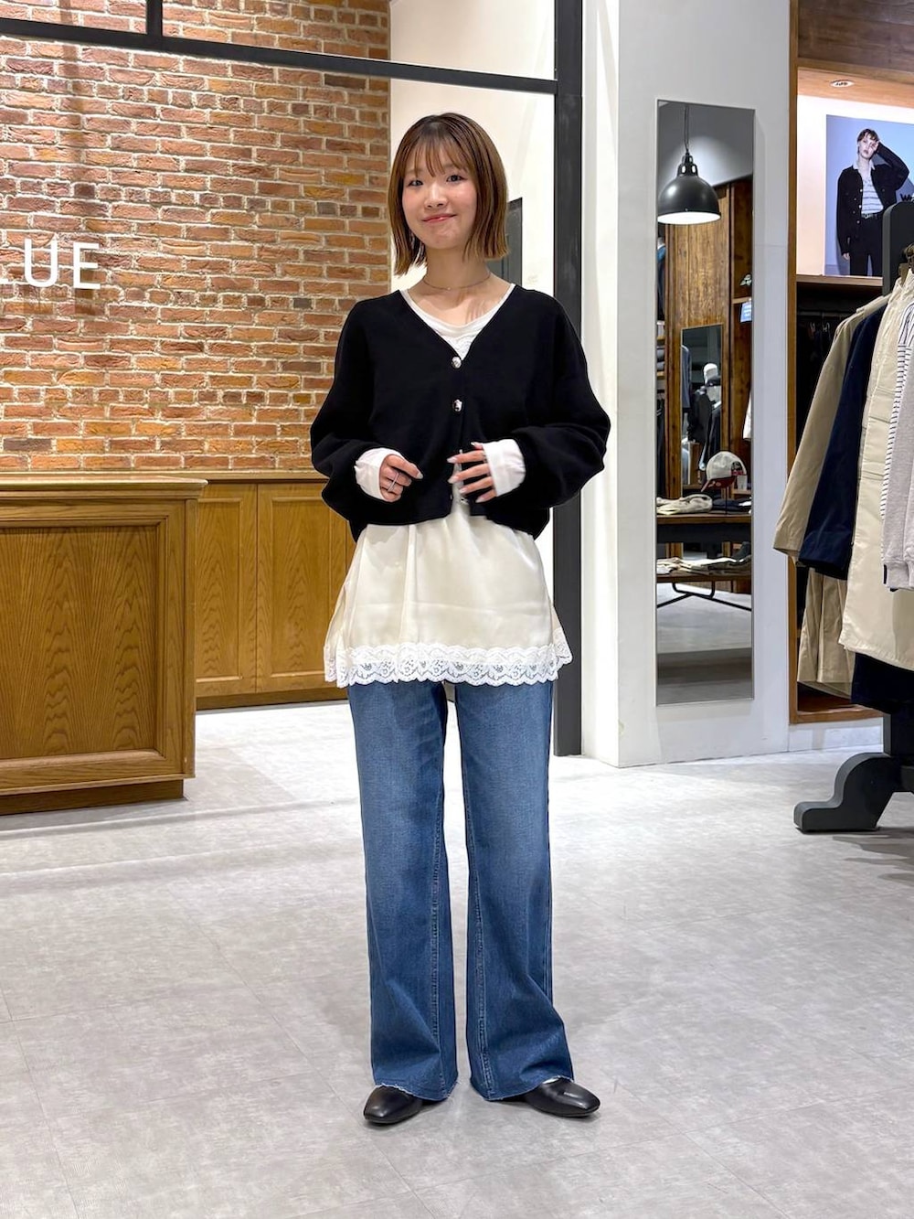 ブラック系のパンプス、ブルー系のデニムパンツ、ホワイト系のキャミソールを着用したレディースの春コーディネートの2枚目の写真