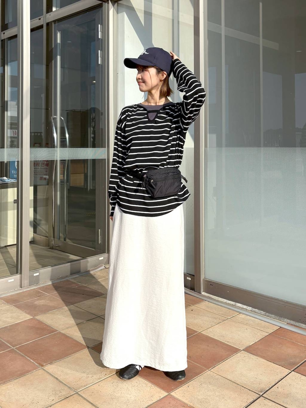 ブラック系のボディバッグ/ウエストポーチ、グレー系のTシャツ/カットソー、ホワイト系のスカートを着用したレディースの春コーディネートの3枚目の写真