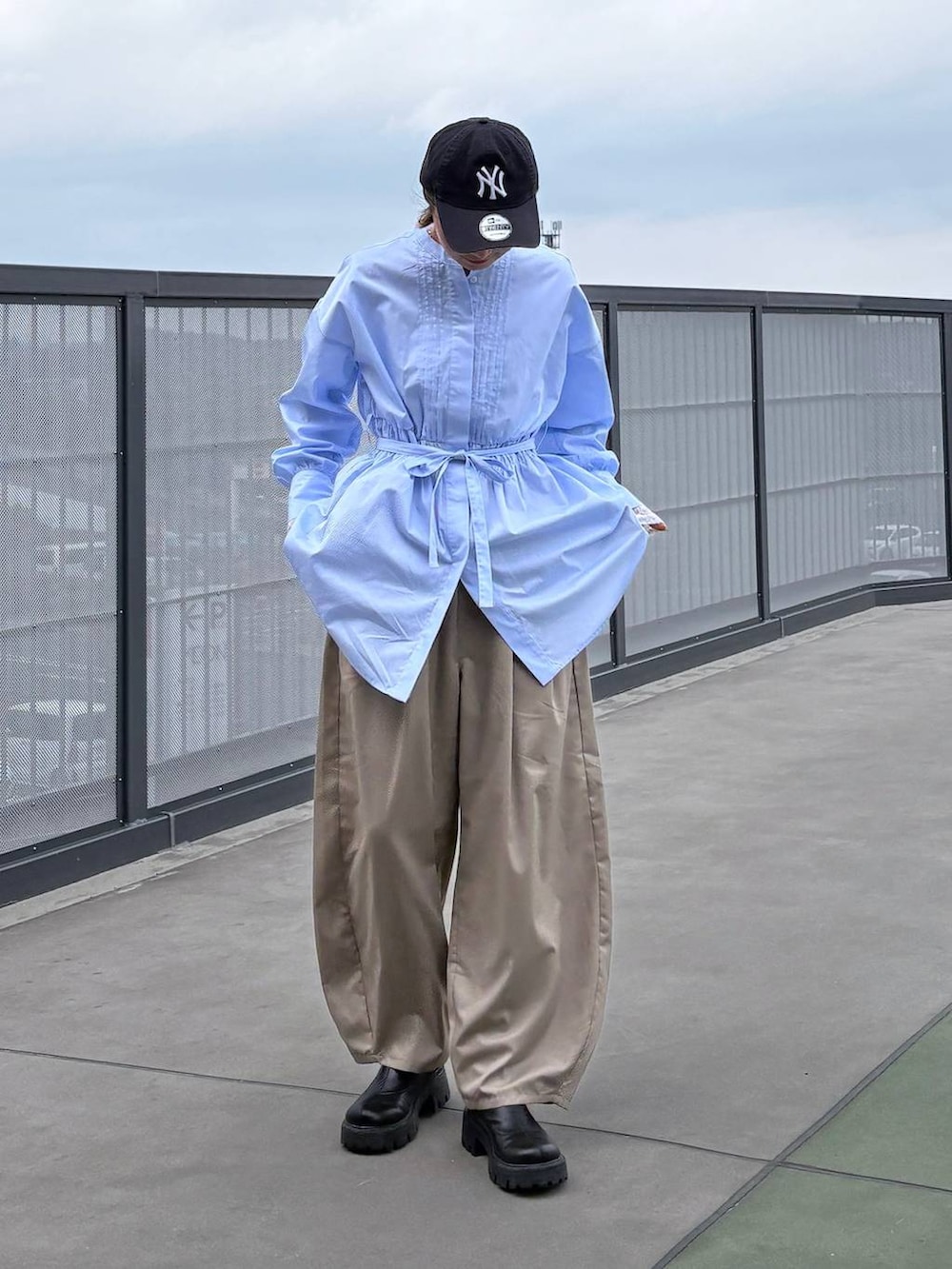 ベージュ系のスラックス、ブルー系のシャツ/ブラウスを着用したレディースの春コーディネートの2枚目の写真