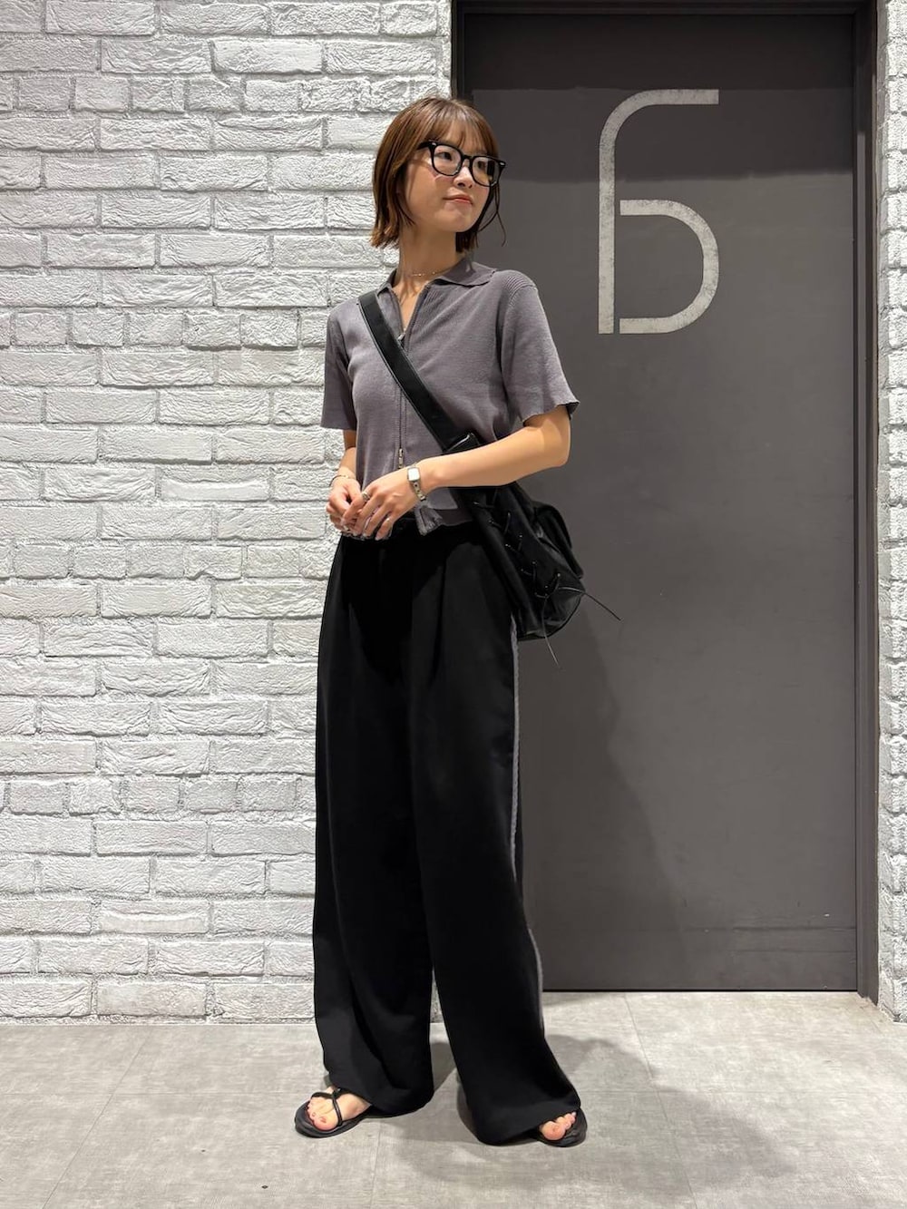 グレー系のニット/セーター、ブラック系のスウェットパンツ、ブラック系のショルダーバッグを着用したレディースの夏コーディネートの2枚目の写真