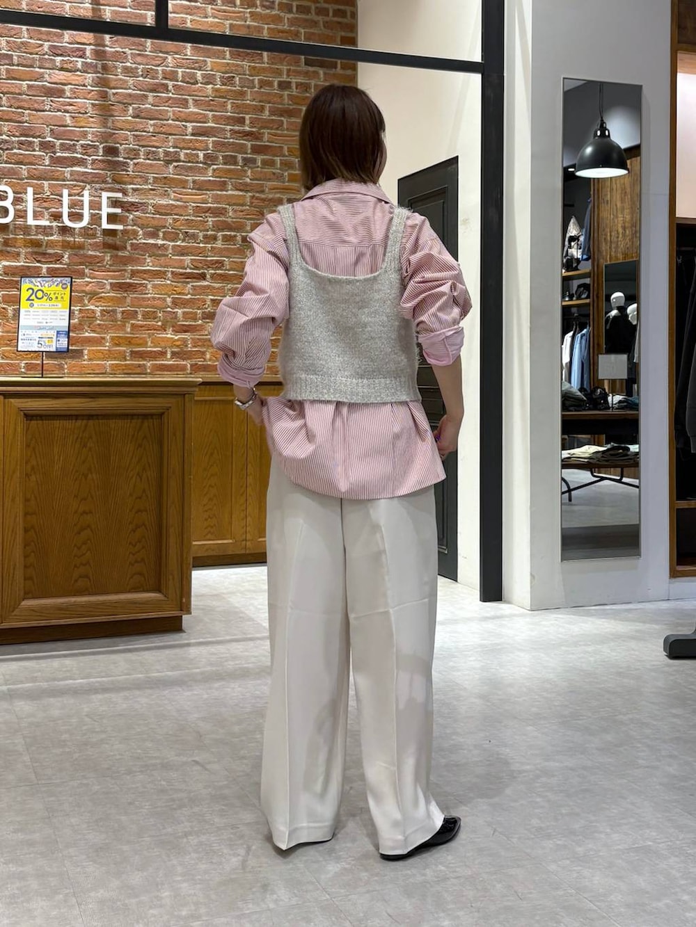 グレー系のニット/セーター、ブラック系のパンプス、ピンク系のシャツ/ブラウスを着用したレディースの春コーディネートの3枚目の写真