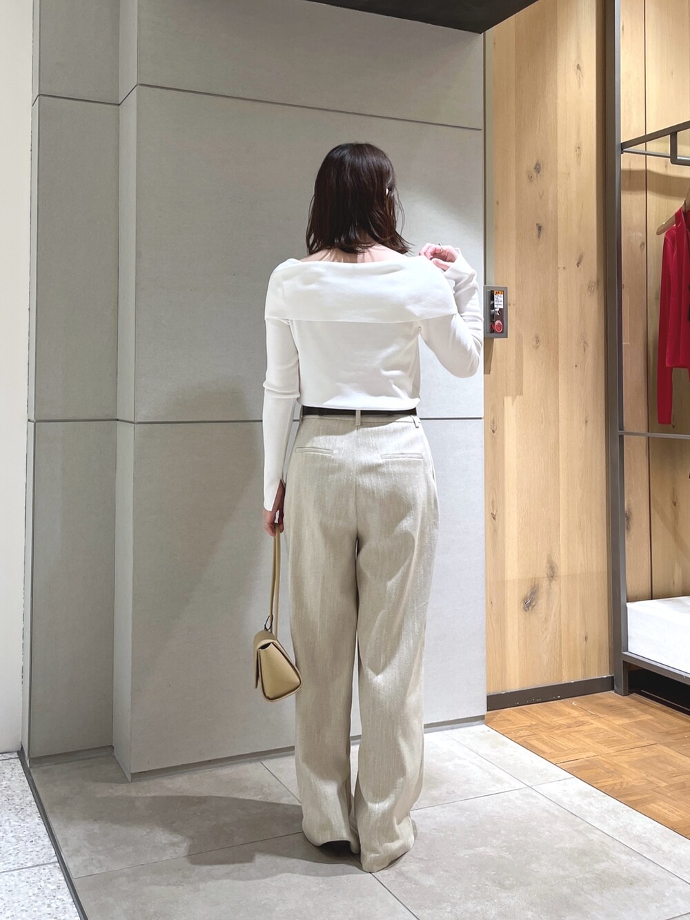 ホワイト系のニット/セーター、ベージュ系のスラックス、ベージュ系のハンドバッグを着用したレディースの春コーディネートの2枚目の写真