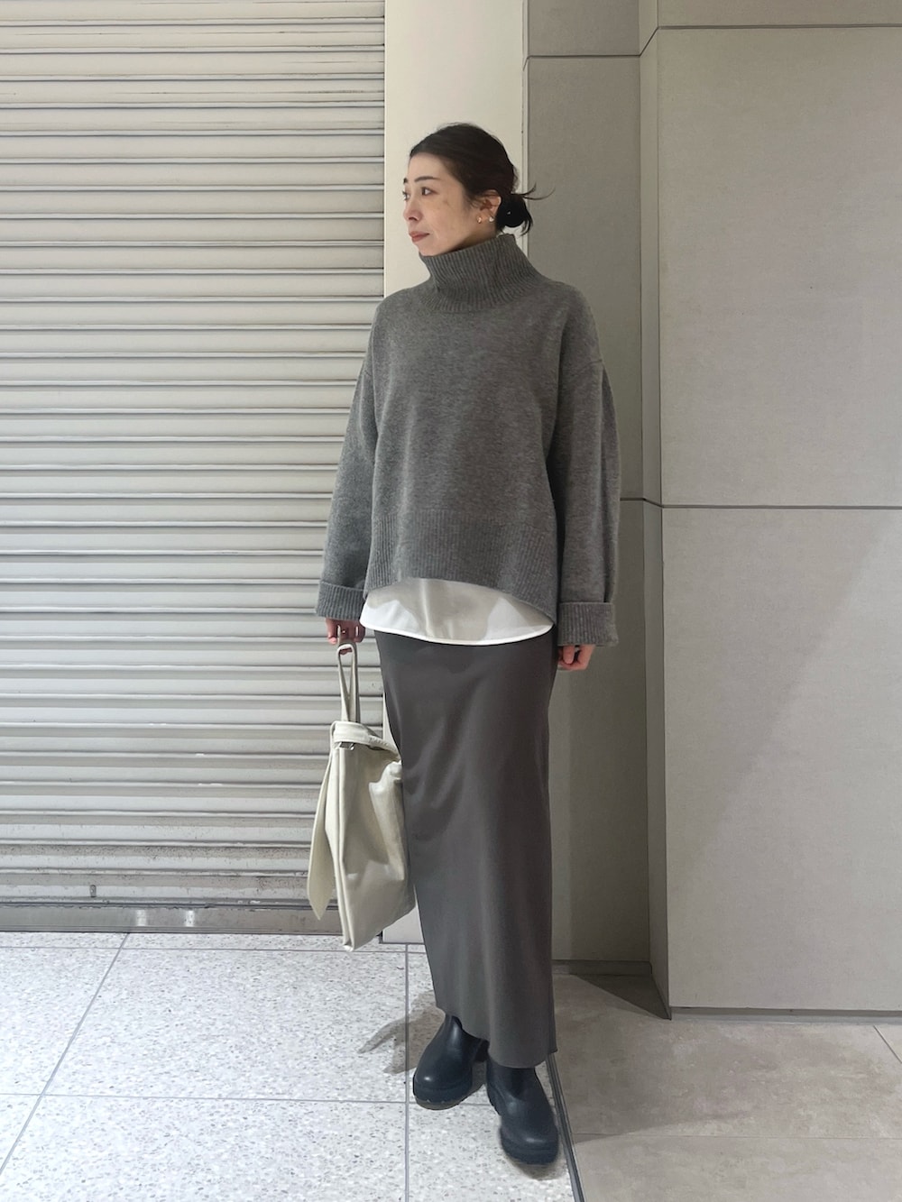 グレー系のニット/セーター、ホワイト系のシャツ/ブラウス、グレー系のスカートを着用したレディースの秋コーディネートの3枚目の写真