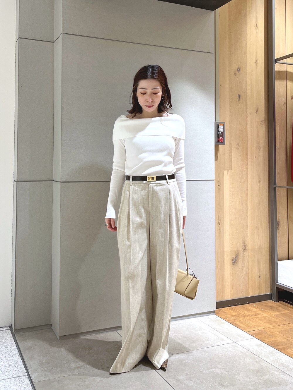ホワイト系のニット/セーター、ベージュ系のスラックス、ベージュ系のハンドバッグを着用したレディースの春コーディネートの3枚目の写真