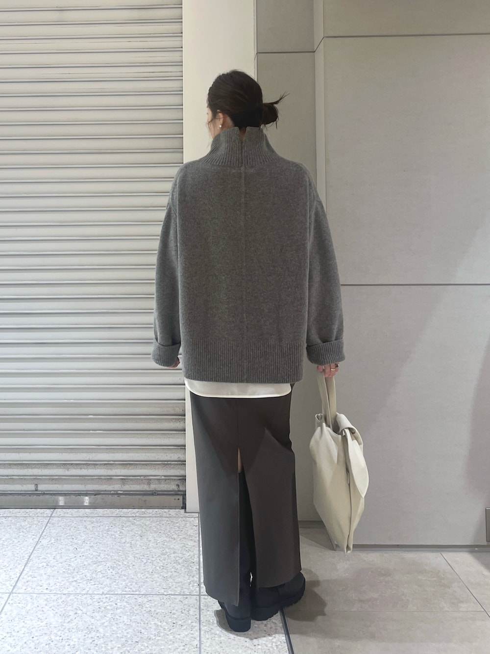 グレー系のニット/セーター、ホワイト系のシャツ/ブラウス、グレー系のスカートを着用したレディースの秋コーディネートの2枚目の写真