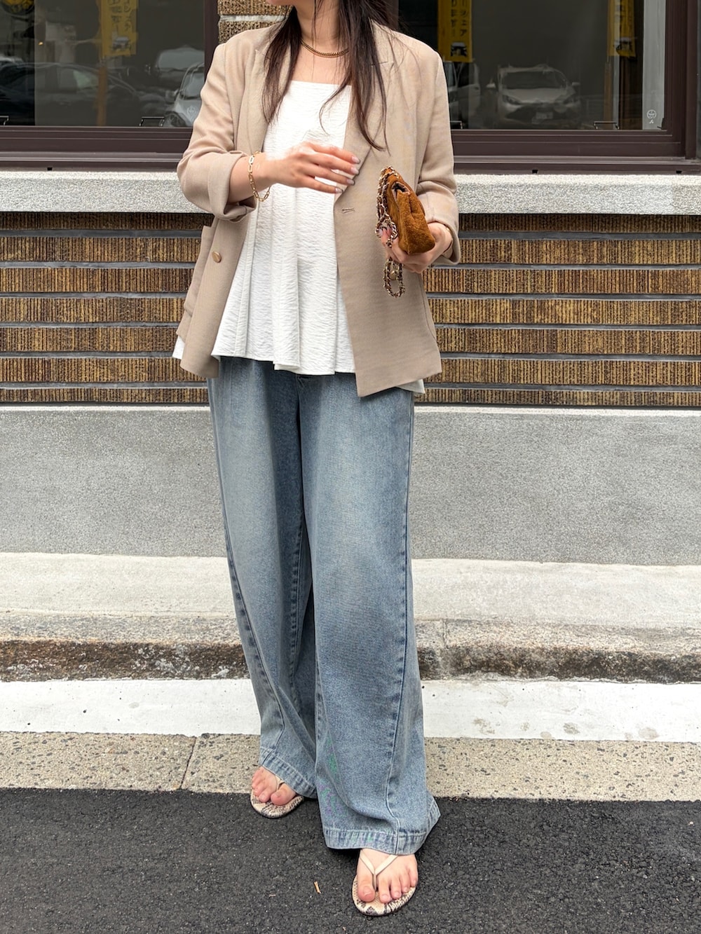 ベージュ系のテーラードジャケット、ブルー系のデニムパンツ、ホワイト系のキャミソールを着用したレディースの春コーディネートの5枚目の写真