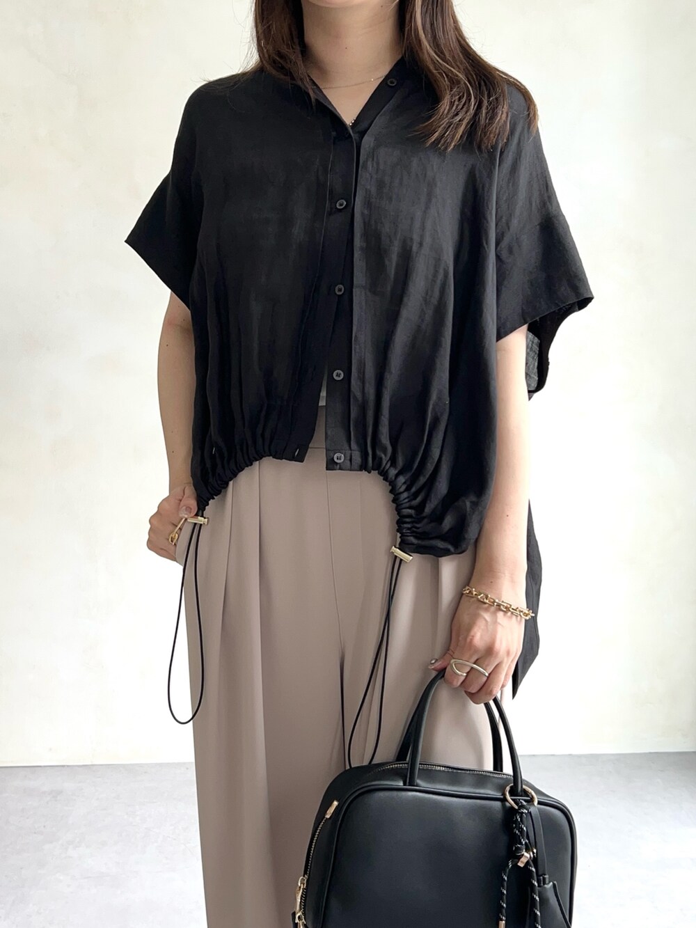 ブラック系のシャツ/ブラウス、ホワイト系のTシャツ/カットソー、ベージュ系のスラックスを着用したレディースの夏コーディネートの3枚目の写真