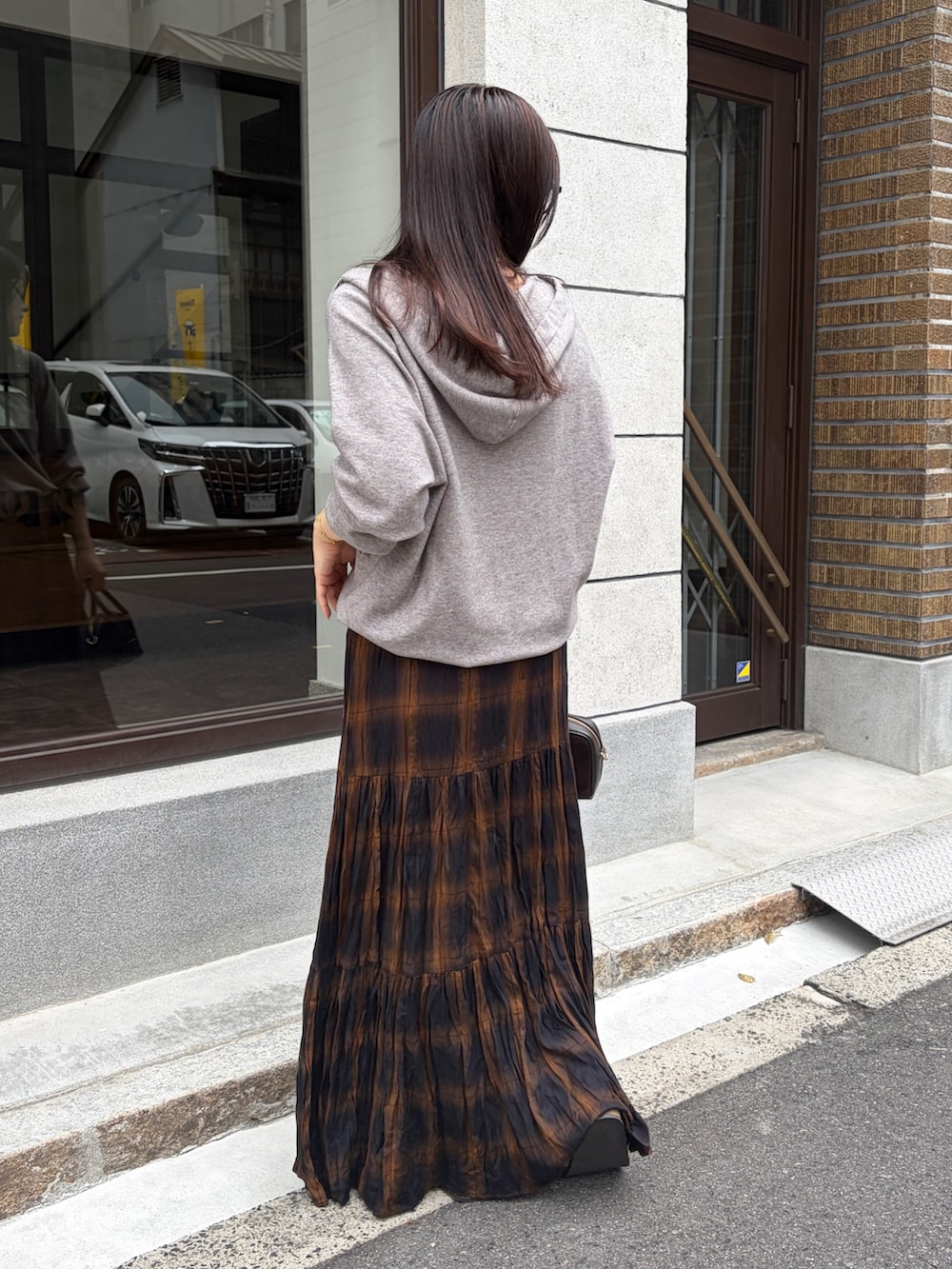 グレー系のニット/セーター、ブラウン系のスカート、ブラウン系のトートバッグを着用したレディースの秋コーディネートの2枚目の写真