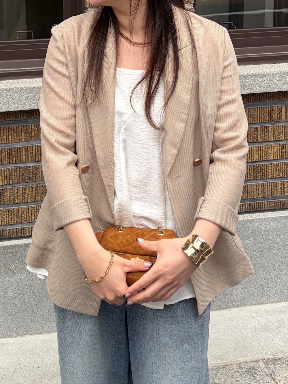 ベージュ系のテーラードジャケット、ブルー系のデニムパンツ、ホワイト系のキャミソールを着用したレディースの春コーディネートの3枚目の写真