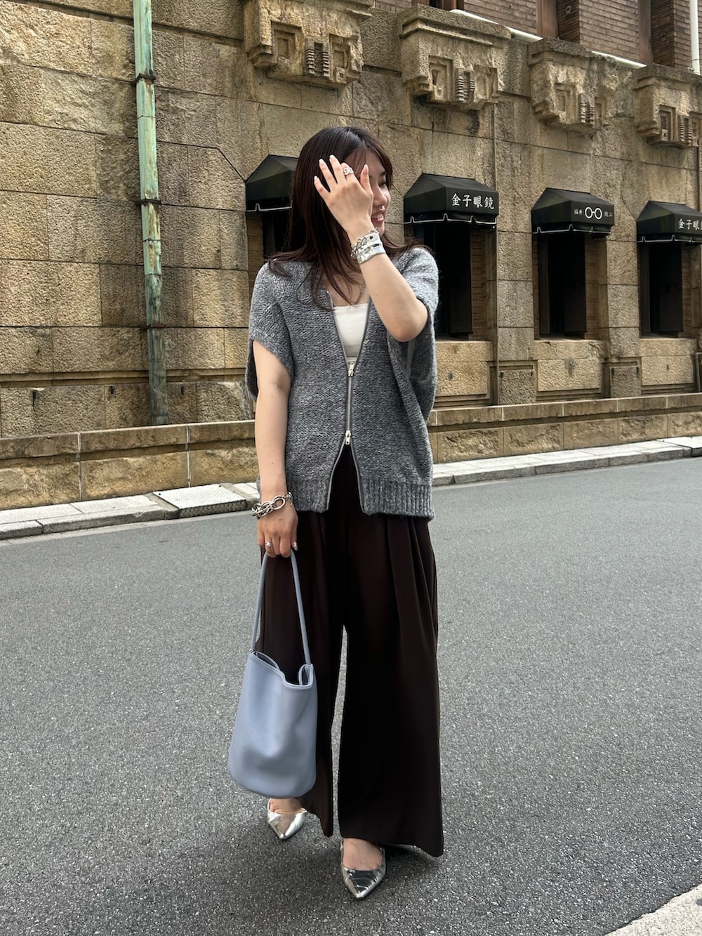 グレー系のカーディガン/ボレロ、ブラウン系のスラックス、ブルー系のショルダーバッグを着用したレディースの夏コーディネートの2枚目の写真