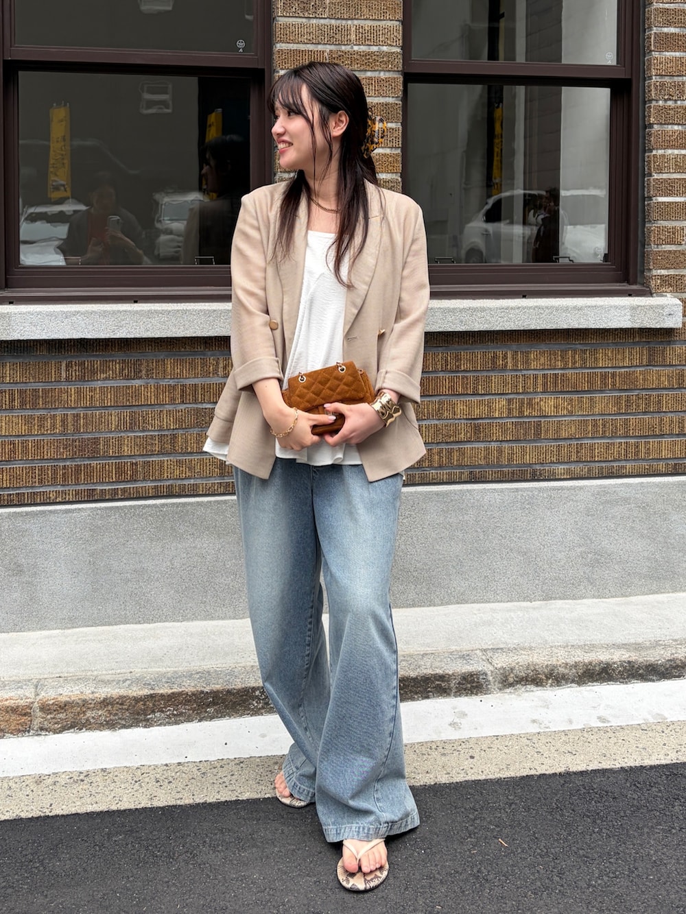 ベージュ系のテーラードジャケット、ブルー系のデニムパンツ、ホワイト系のキャミソールを着用したレディースの春コーディネートの2枚目の写真