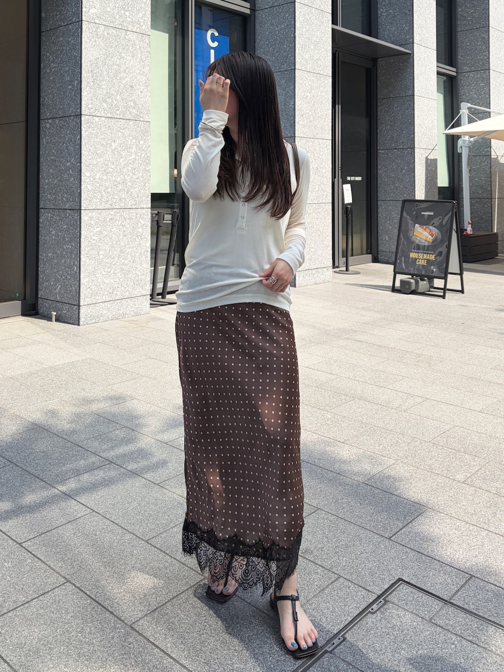 ホワイト系のTシャツ/カットソー、ブラウン系のスカート、グリーン系のトートバッグを着用したレディースの夏コーディネートの3枚目の写真