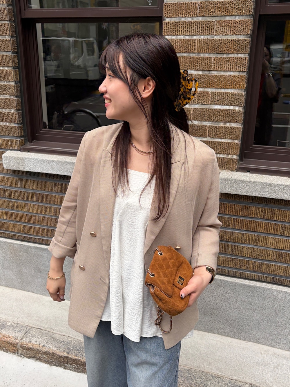 ベージュ系のテーラードジャケット、ブルー系のデニムパンツ、ホワイト系のキャミソールを着用したレディースの春コーディネートの4枚目の写真