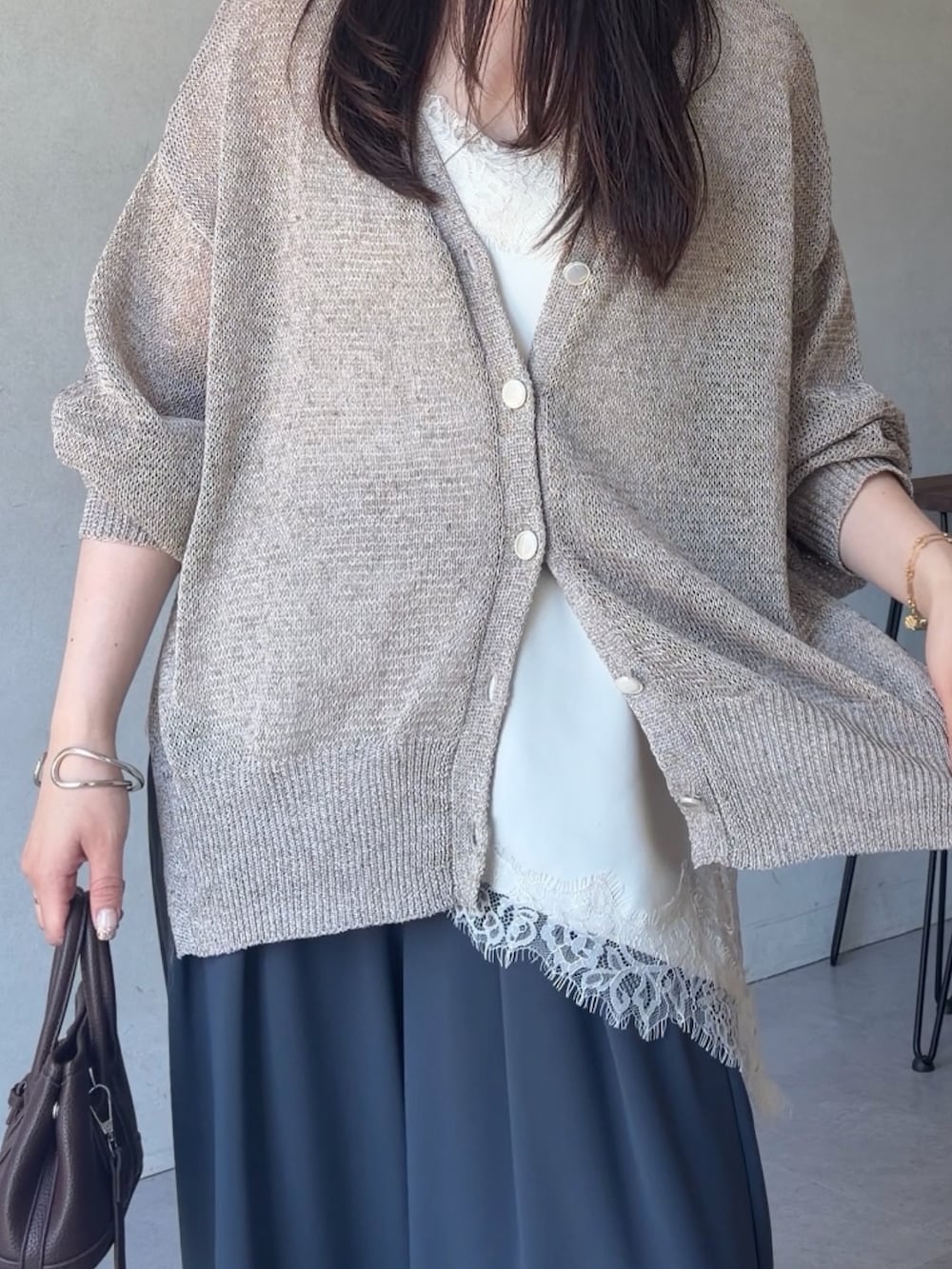 ベージュ系のカーディガン/ボレロ、ホワイト系のシャツ/ブラウス、グレー系のスラックスを着用したレディースの夏コーディネートの3枚目の写真