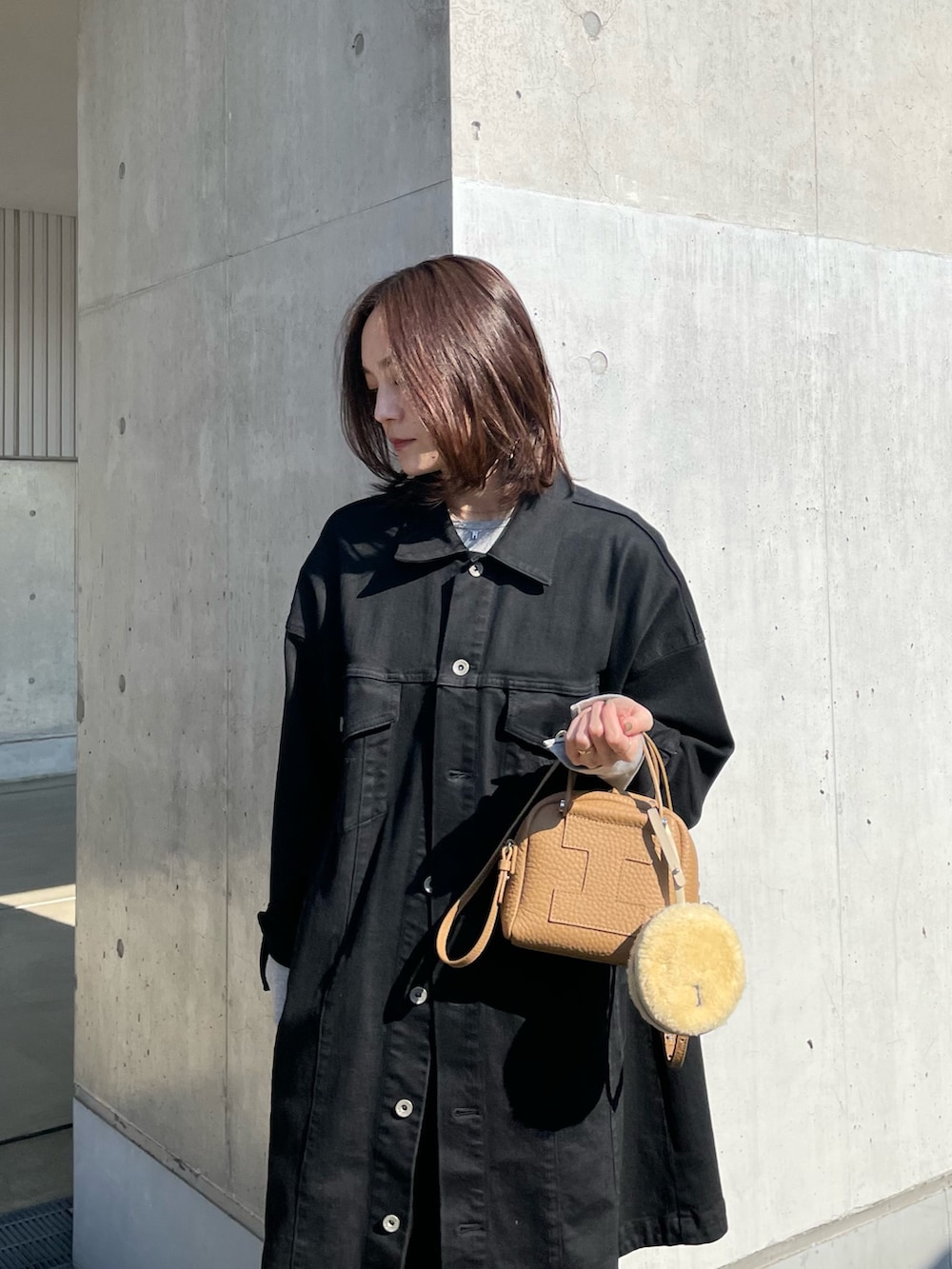 イエロー系のトートバッグ、ホワイト系のその他小物を着用したレディースの冬コーディネートの2枚目の写真