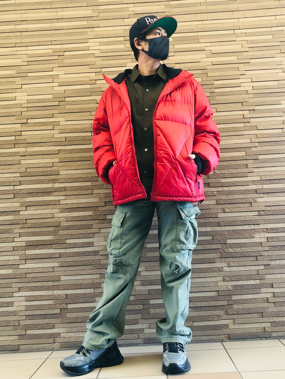グレー系のスニーカー、グリーン系のカーゴパンツ、レッド系のダウンジャケット/コートを着用したメンズの冬コーディネートの2枚目の写真