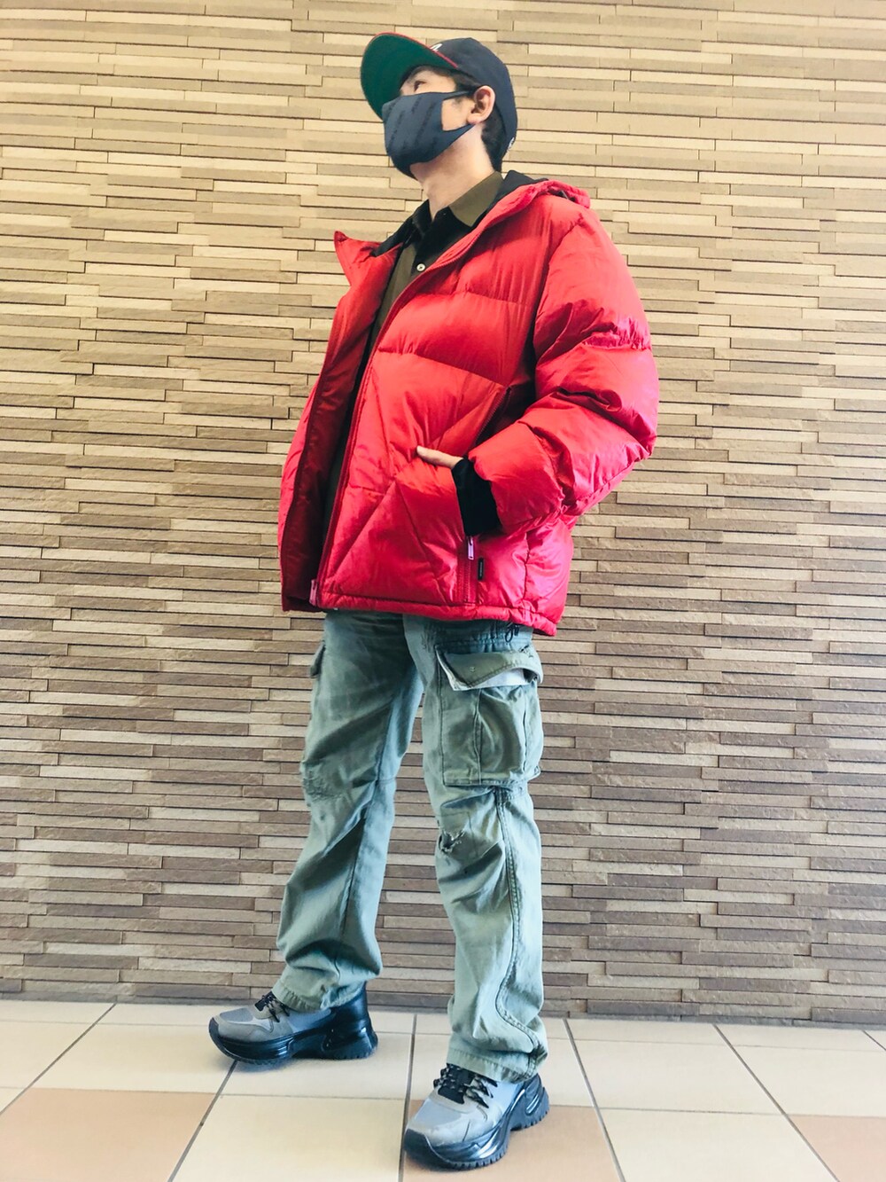 グレー系のスニーカー、グリーン系のカーゴパンツ、レッド系のダウンジャケット/コートを着用したメンズの冬コーディネートの4枚目の写真