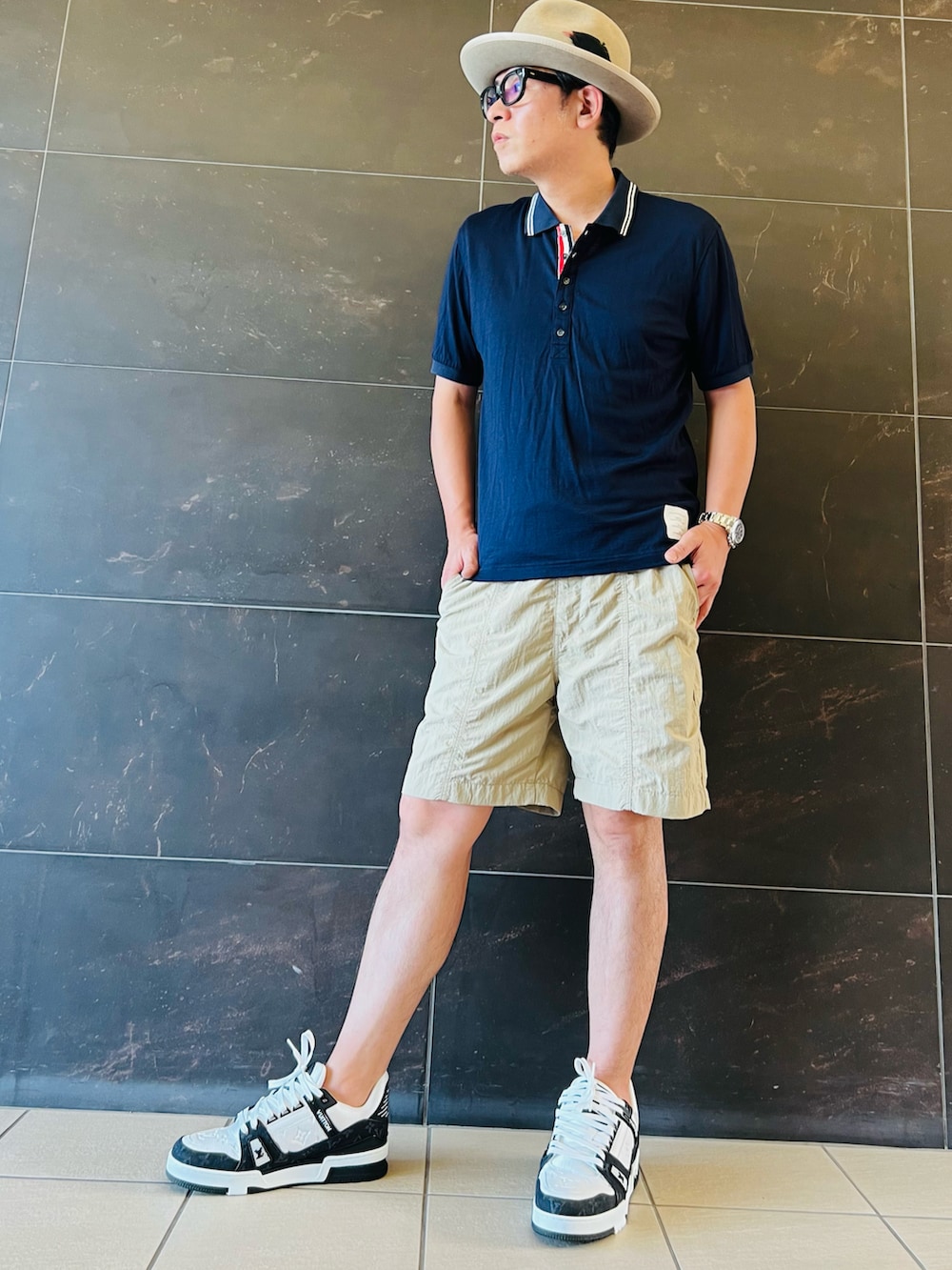 ブラック系のスニーカー、ベージュ系のその他パンツ、ブルー系のポロシャツを着用したメンズの夏コーディネートの2枚目の写真