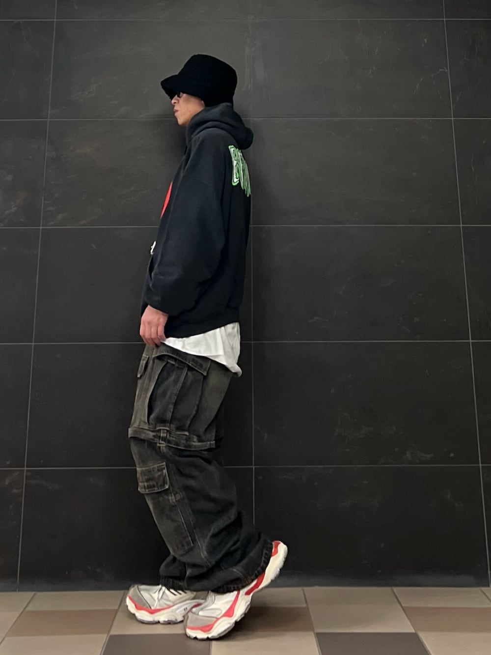 ブラック系のデニムパンツ、ブラック系のパーカー、ホワイト系のスニーカーを着用したメンズの秋コーディネートの3枚目の写真