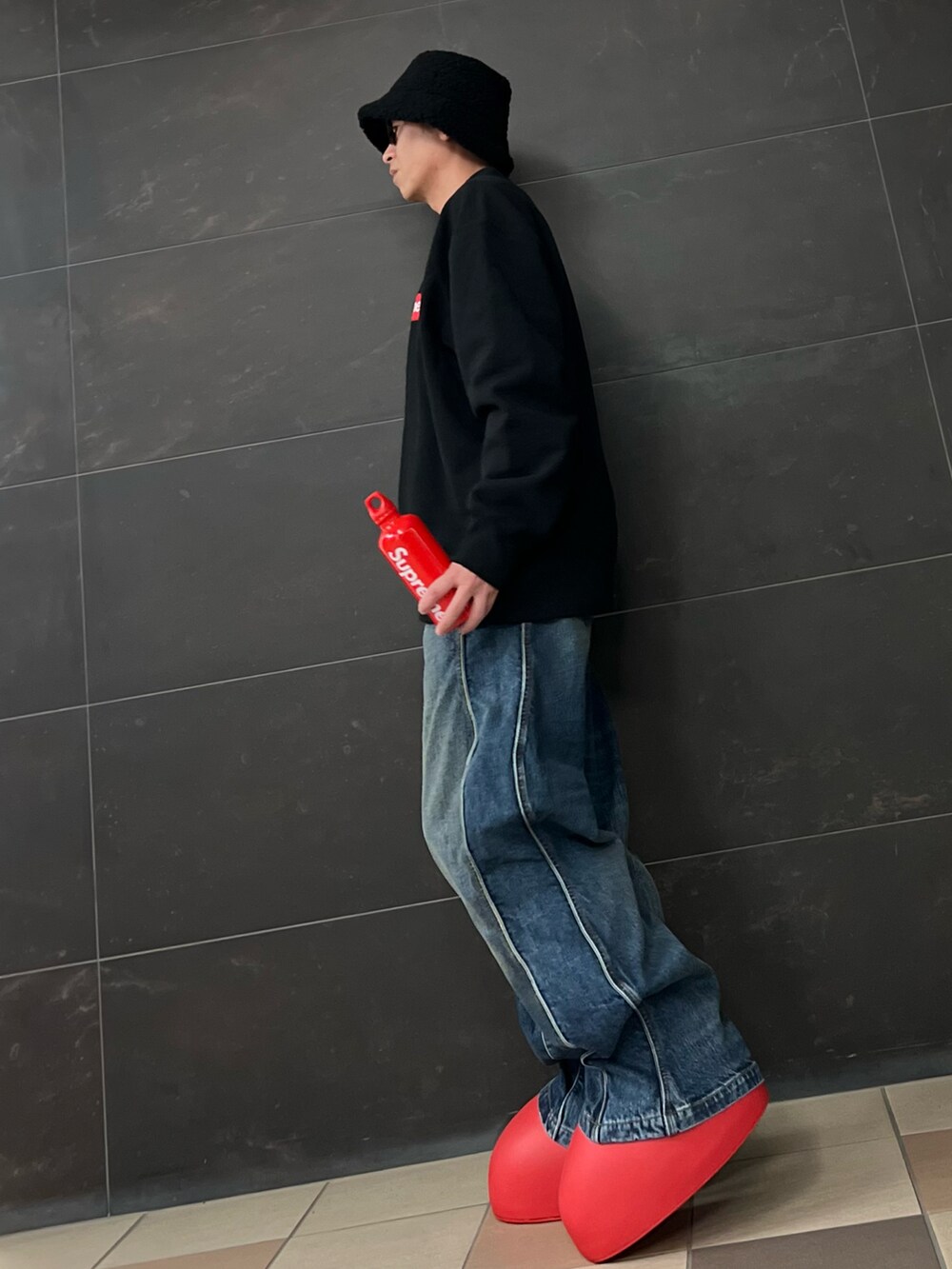 ブラック系のスウェット、ブルー系のデニムパンツ、レッド系のブーツを着用したメンズの夏コーディネートの5枚目の写真