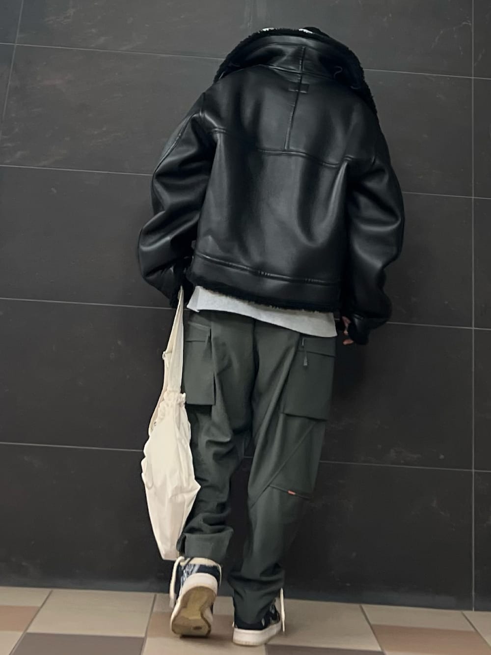 グレー系のカーゴパンツ、ホワイト系のショルダーバッグ、グレー系のパーカーを着用したメンズの冬コーディネートの2枚目の写真