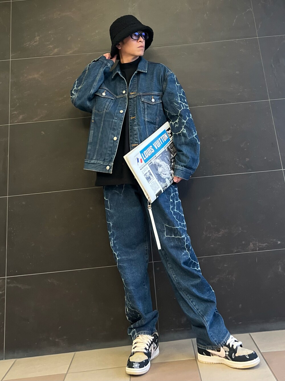 ブルー系のデニムパンツ、ブルー系のデニムジャケット、ホワイト系のハンドバッグを着用したメンズの春コーディネートの2枚目の写真