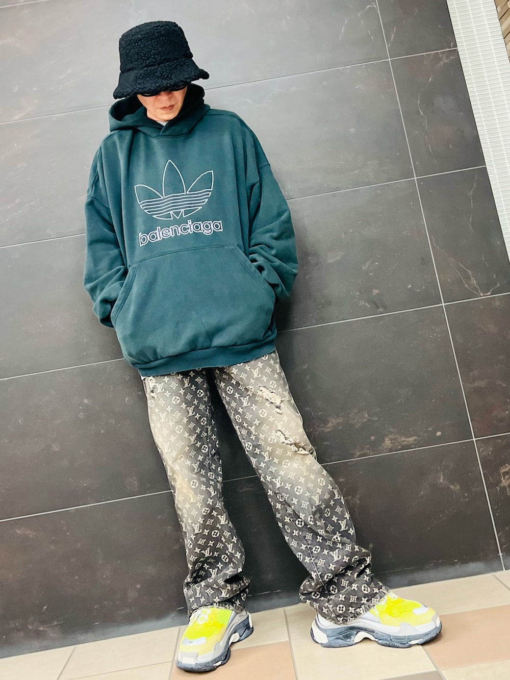 ブラック系のデニムパンツ、グリーン系のパーカー、イエロー系のスニーカーを着用したメンズの冬コーディネートの2枚目の写真