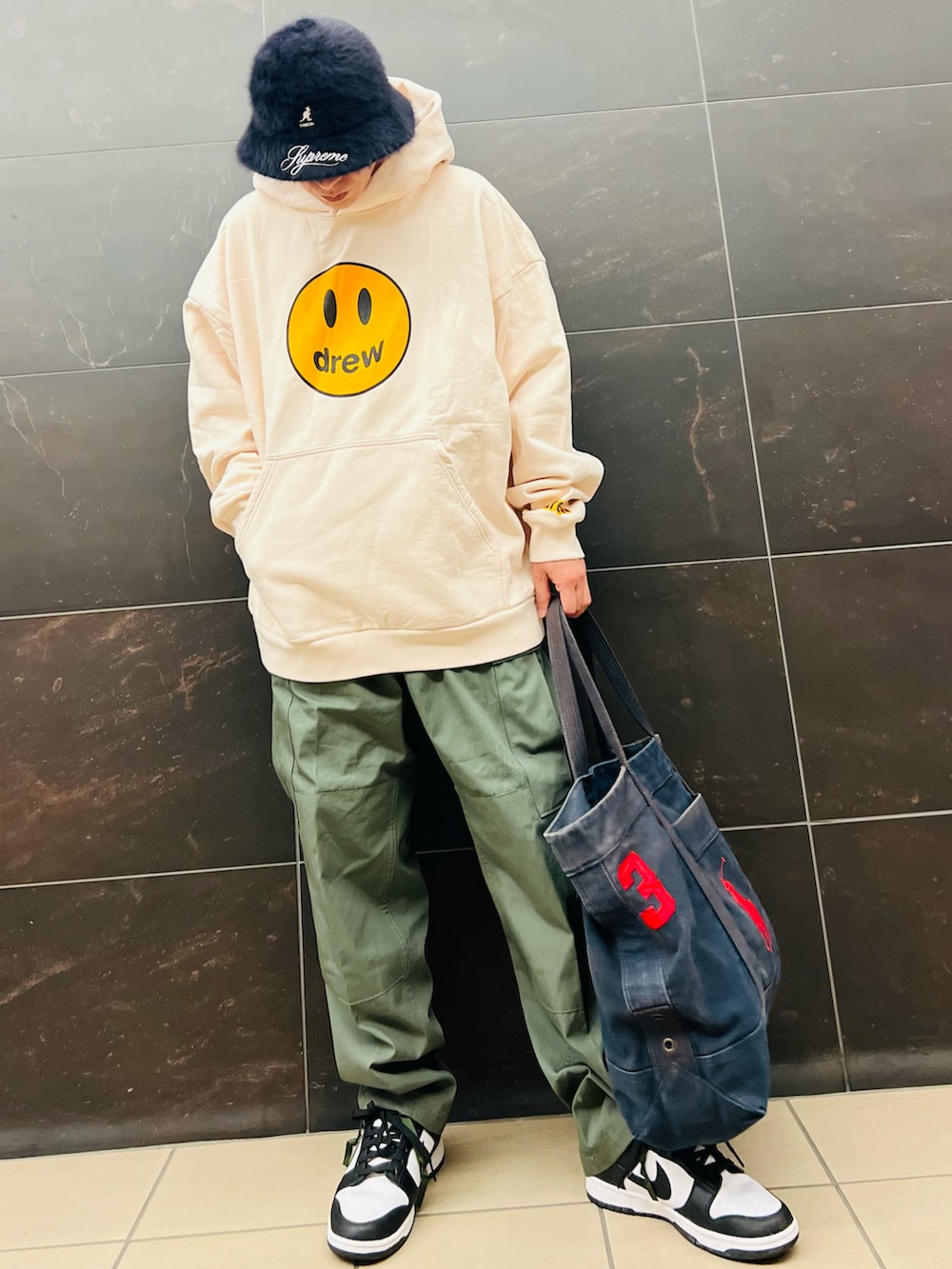 ベージュ系のパーカー、グリーン系のカーゴパンツ、ブラック系のスニーカーを着用したメンズの秋コーディネートの2枚目の写真