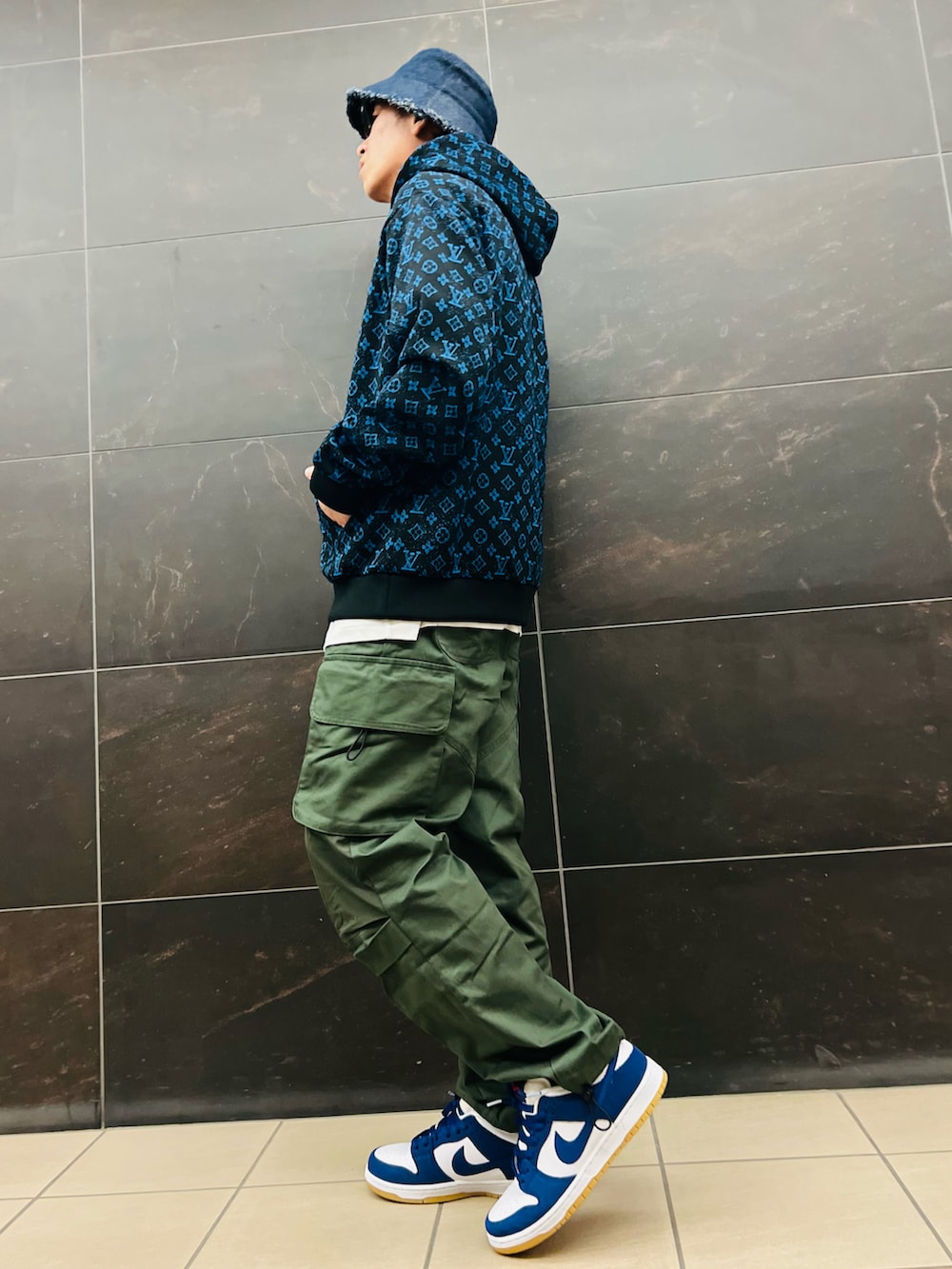 グリーン系のカーゴパンツ、ブルー系のパーカー、ブルー系のスニーカーを着用したメンズの秋コーディネートの2枚目の写真