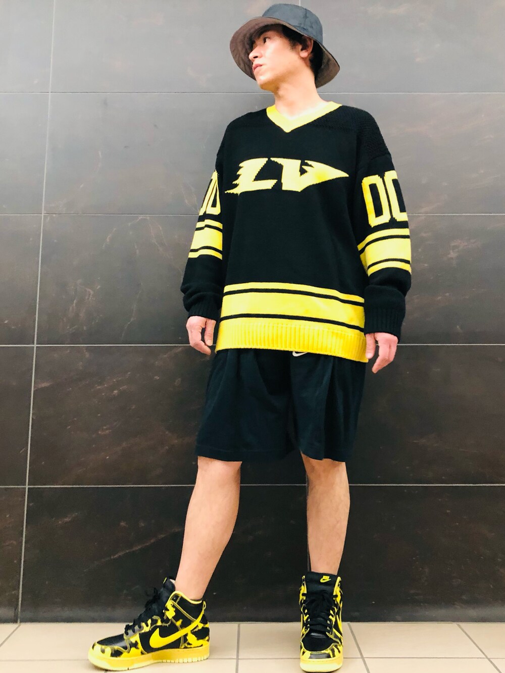 イエロー系のニット/セーター、ブラック系のスウェットパンツ、イエロー系のスニーカーを着用したメンズの春コーディネートの2枚目の写真