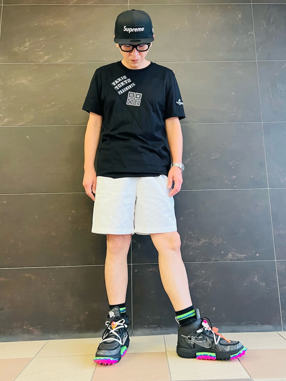 ブラック系のTシャツ/カットソー、ホワイト系のチノパンツ、ブラック系のスニーカーを着用したメンズの夏コーディネートの3枚目の写真