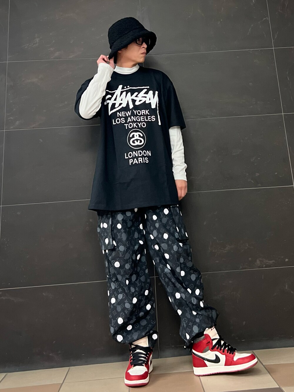 レッド系のスニーカー、ブラック系のカーゴパンツ、ブラック系のTシャツ/カットソーを着用したメンズの春コーディネートの4枚目の写真