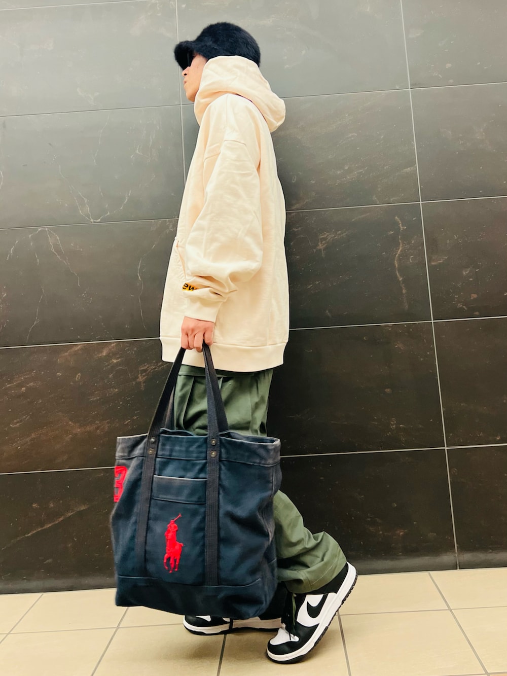 ベージュ系のパーカー、グリーン系のカーゴパンツ、ブラック系のスニーカーを着用したメンズの秋コーディネートの3枚目の写真