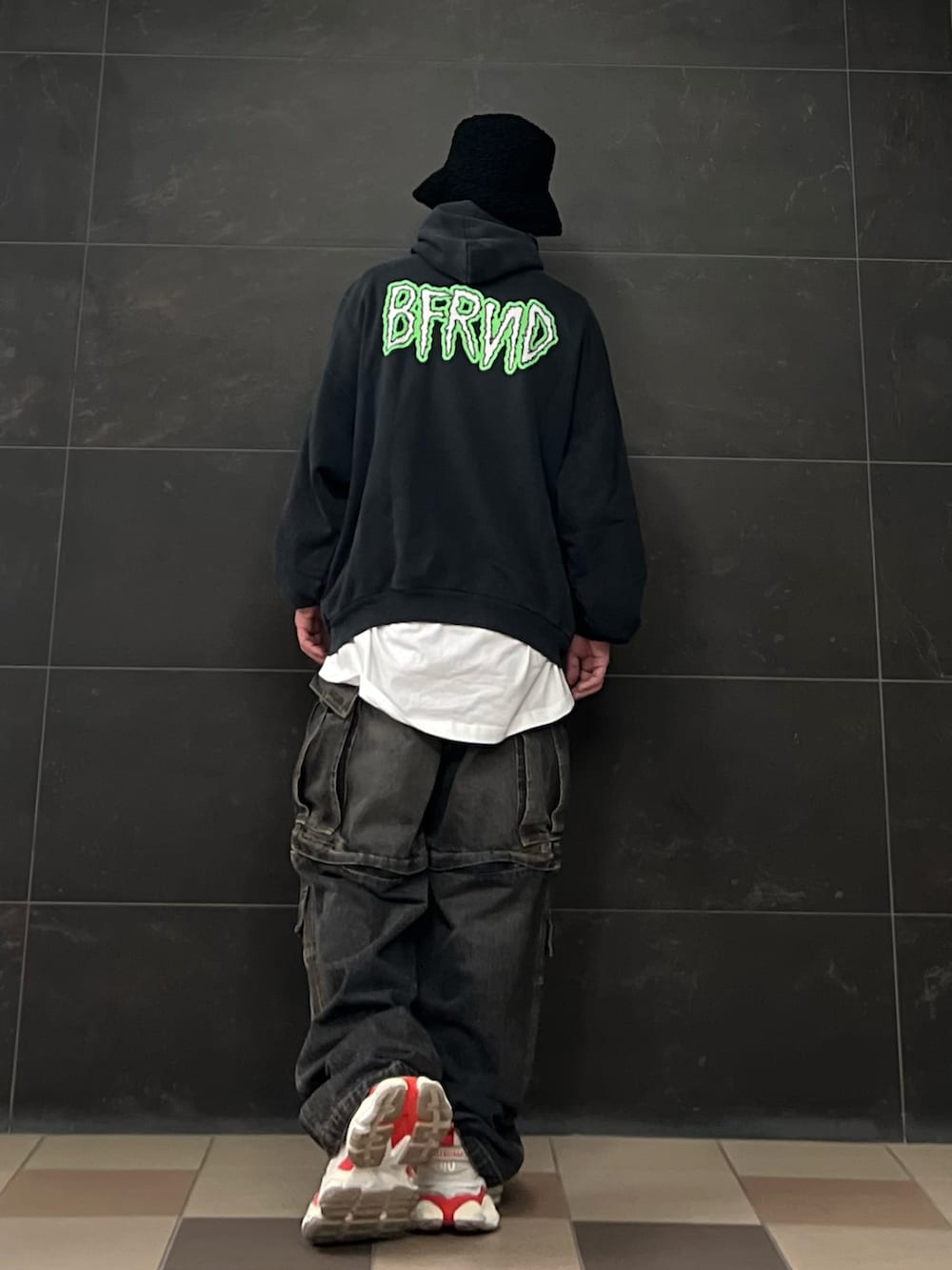 ブラック系のデニムパンツ、ブラック系のパーカー、ホワイト系のスニーカーを着用したメンズの秋コーディネートの4枚目の写真